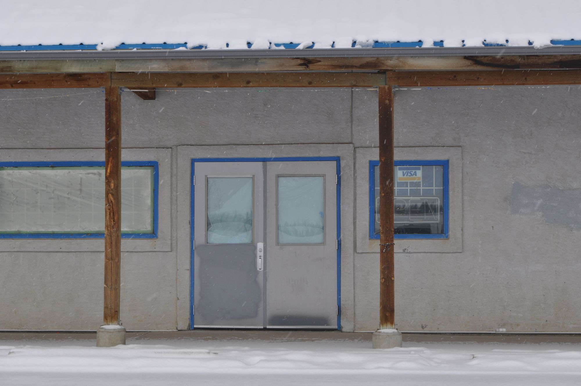 Unit 5, Moccasin Flats Plaza: closed grey double doors, papered windows, snow on the ground